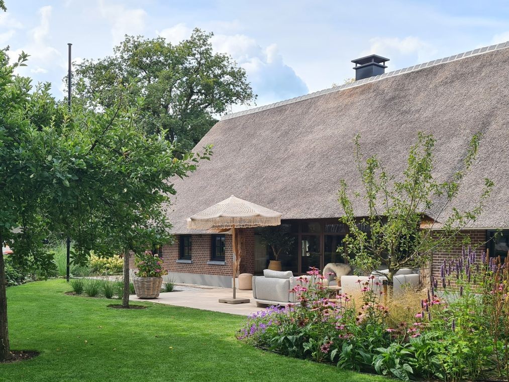 Weelderige beplanting bij een gerenoveerde boerderij