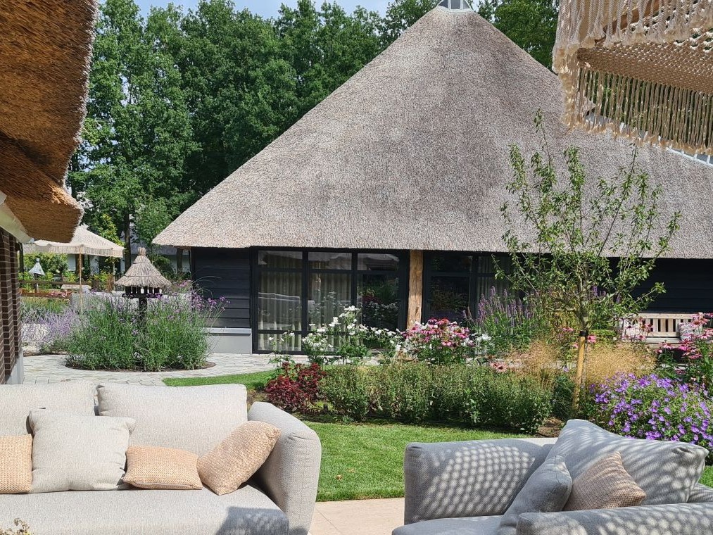 Een rietgedekte boerderij met een luxe maar landelijke tuin