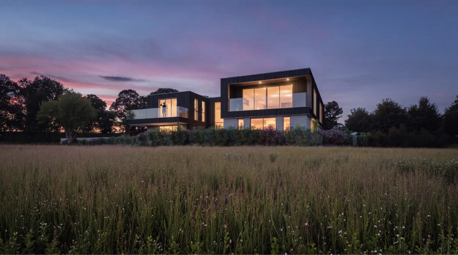 The same meadow view of the house at dusk