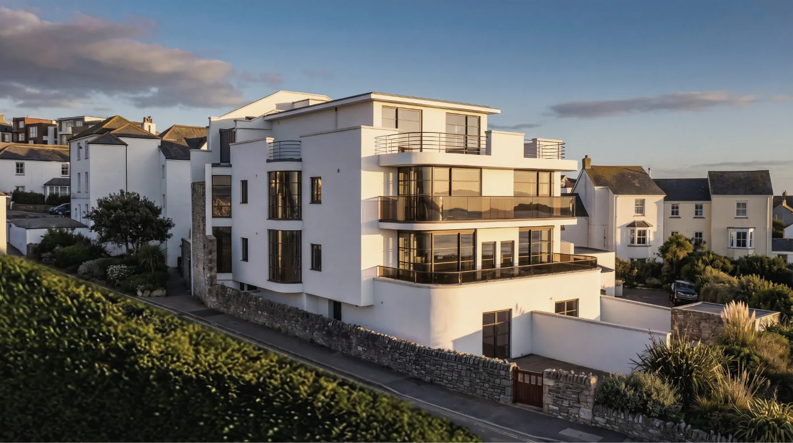 White rendered apartment building with curved balconies above a seaside town