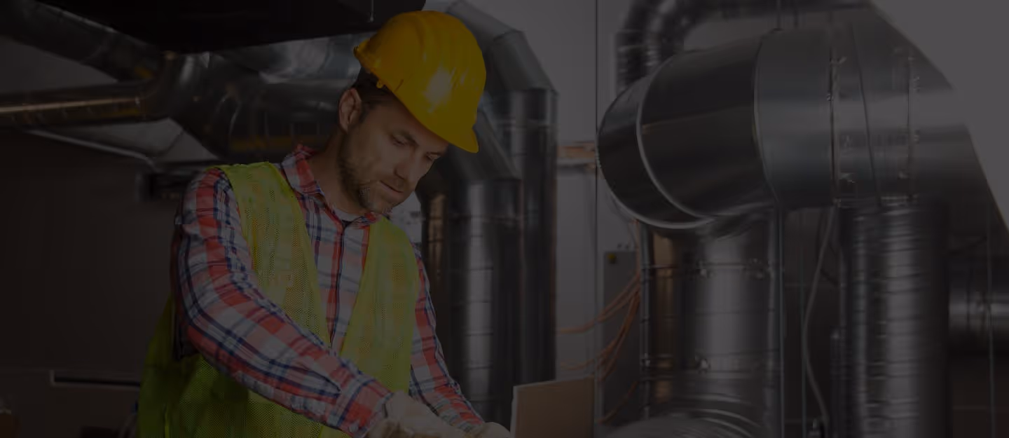 An HVAC technician adjusting controls or fittings on a rooftop air-conditioning unit.