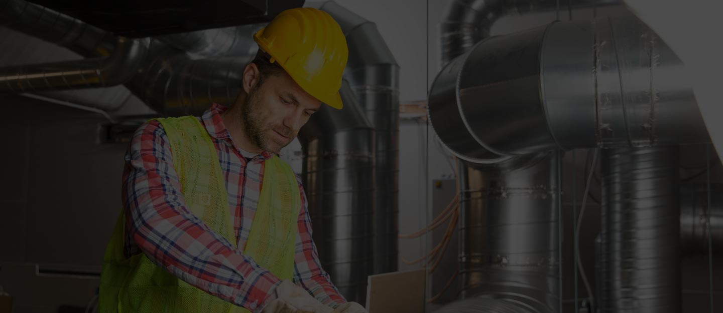 An HVAC technician adjusting controls or fittings on a rooftop air-conditioning unit.