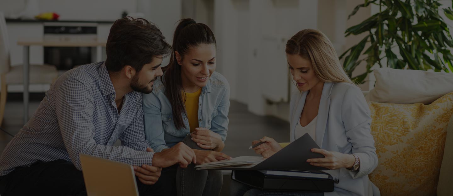 Agents pointing at listings and contract pages spread on a desk in a sunlit office.