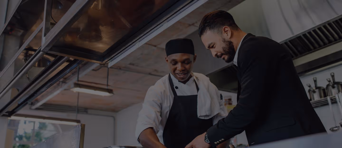Chefs plating dishes and sliding finished plates across a service pass.