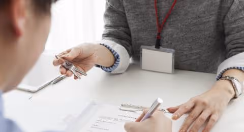 Woman holding keys man signing document