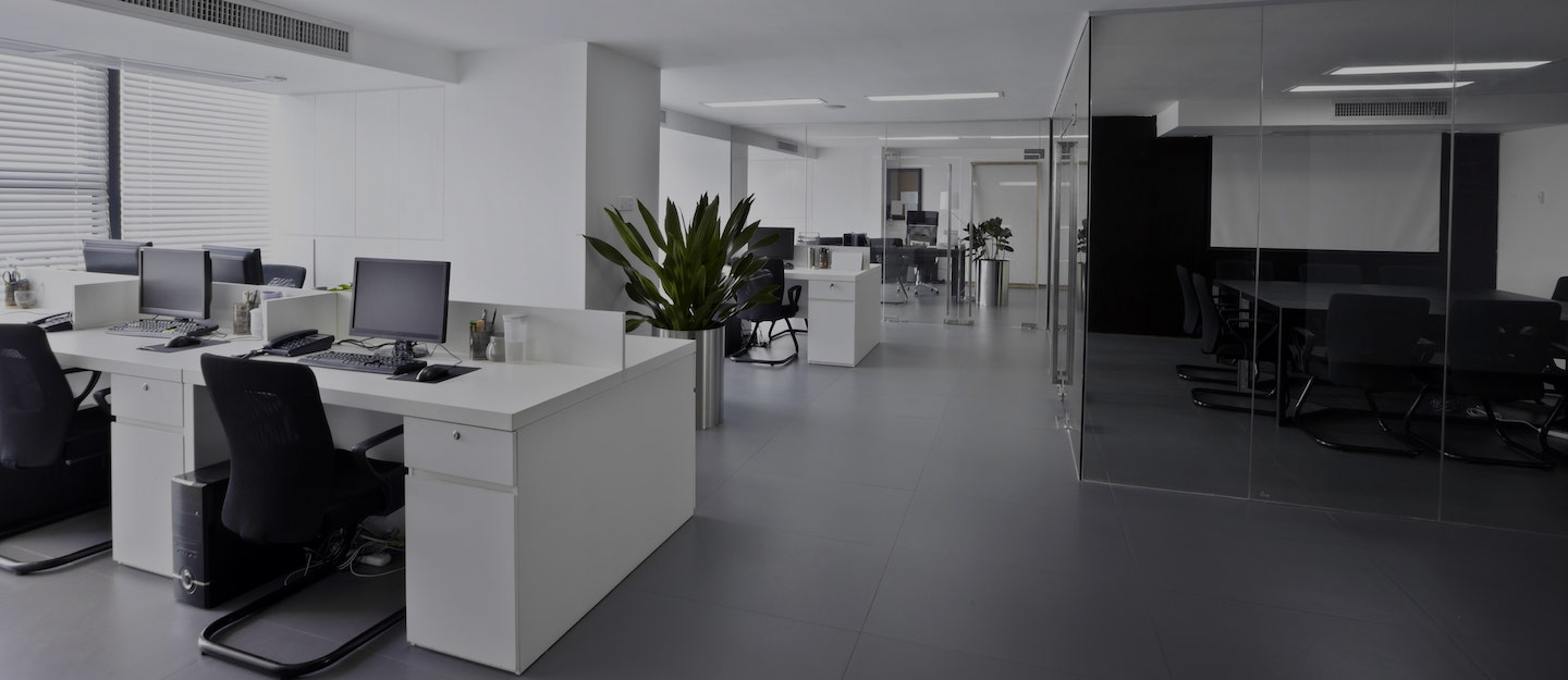 Empty open-plan office with a meeting room behind a glass partition