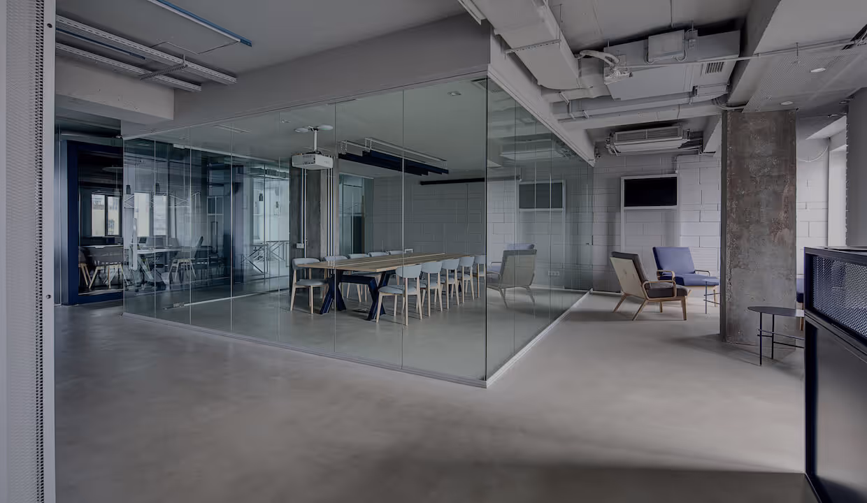 Industrial office setting with an empty meeting room behind a glass partition