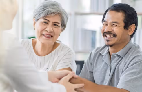 Elderly couple happily shaking hands of advisor