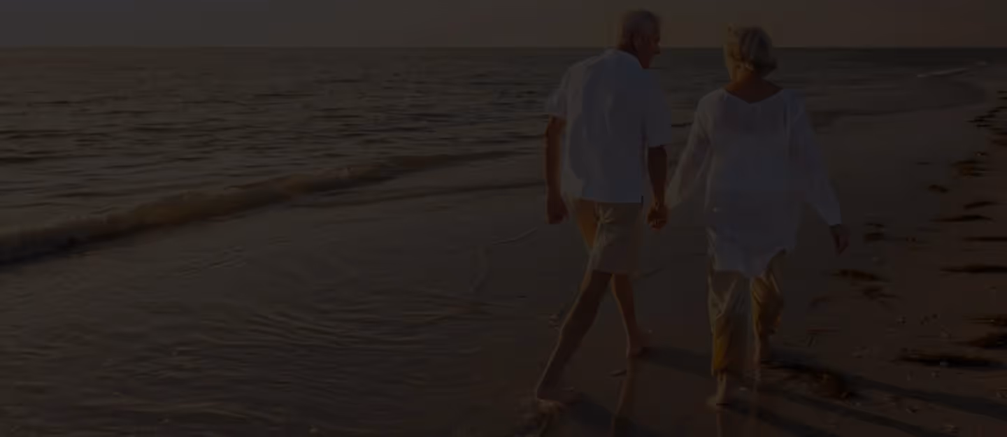 Two mature adults standing outside in relaxed clothing and talking face-to-face.