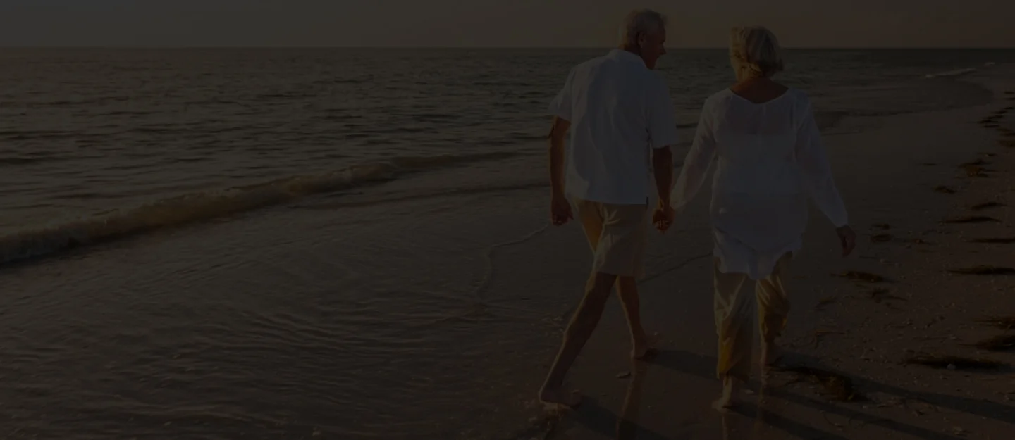 Two mature adults standing outside in relaxed clothing and talking face-to-face.