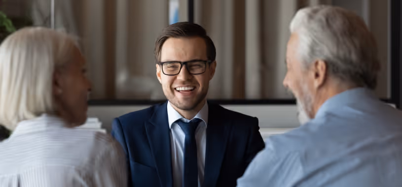 An older couple chatting with their accountant, and all three are laughing.