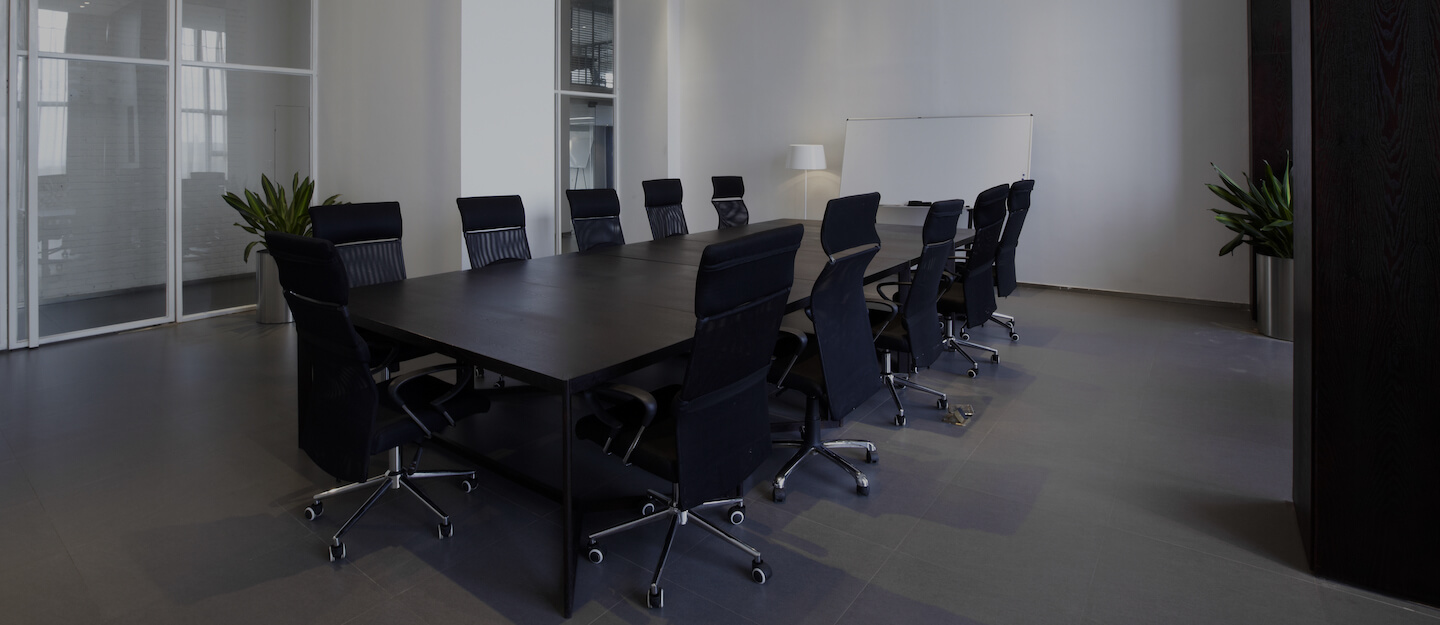 Empty boardroom with black leather chairs around a long table