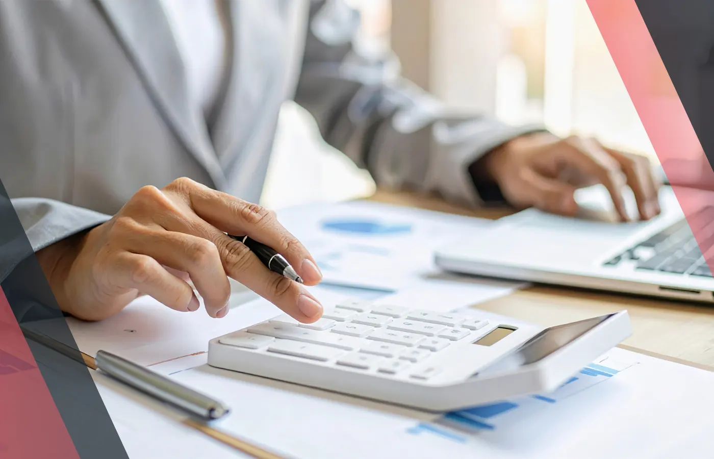 Person calculating figures on a calculator beside financial documents and a laptop.