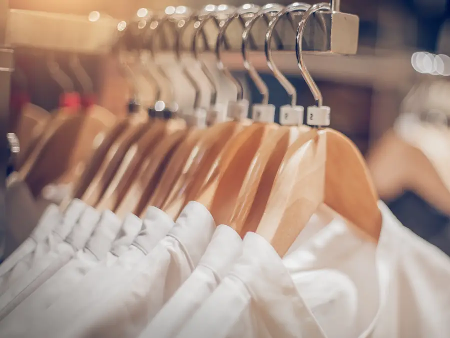 White dress shirts in a hanger hung nicely inside a retail store. 