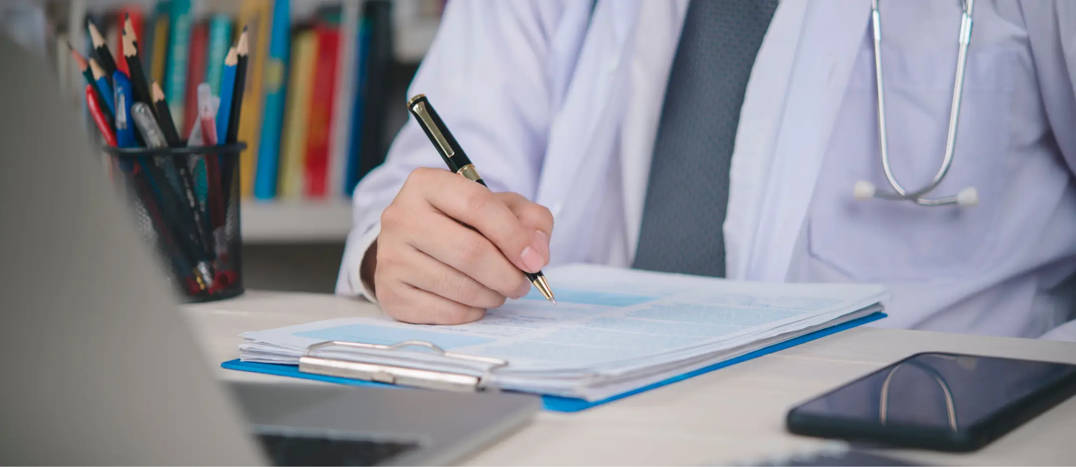 A medical professional working on a patient record while wearing a stethoscope.