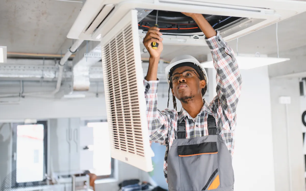 An HVAC specialist working on a ceiling-mounted air conditioning unit