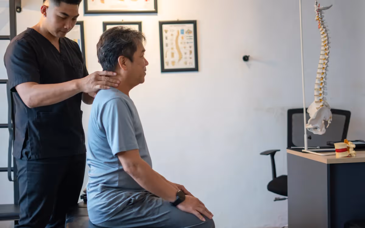 A chiropractic assisting an elderly patient during a session