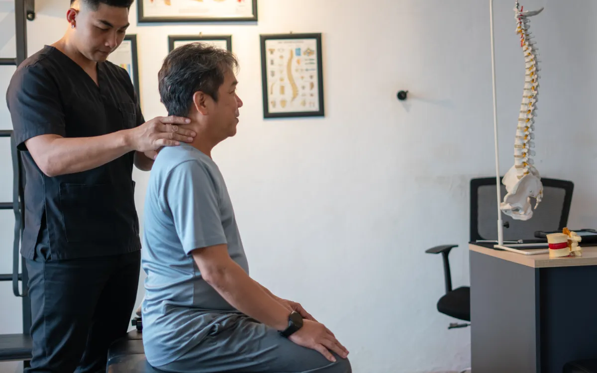 A chiropractic assisting an elderly patient during a session