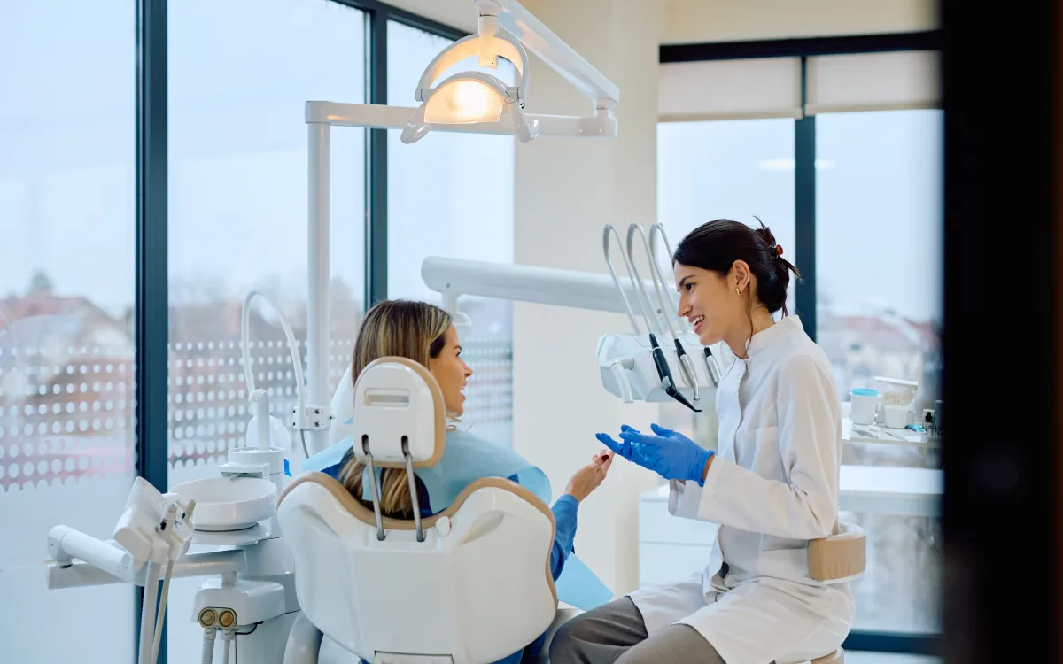 A female dentist wearing blue gloves while explaining the procedure to a patient