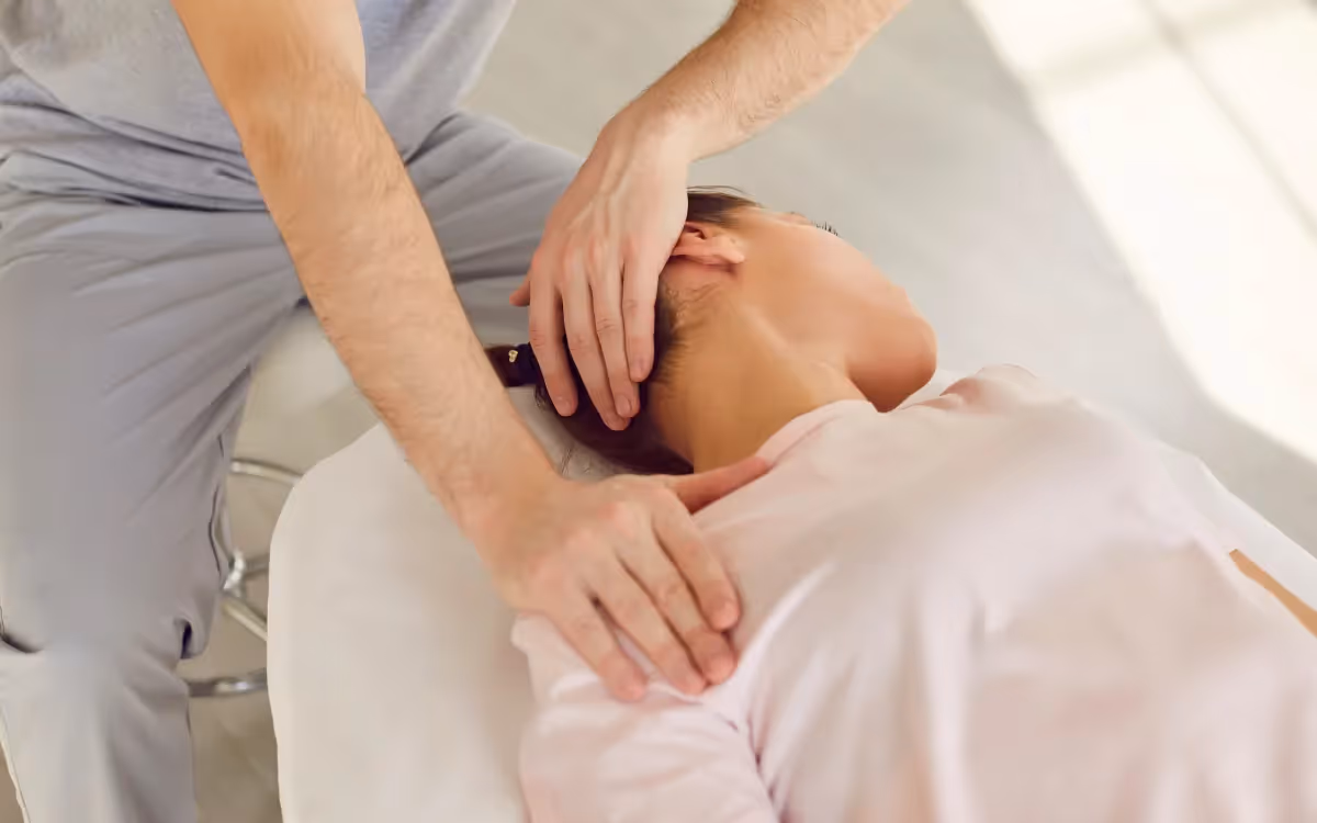 A close up of a hand stretching a patient’s neck during treatment