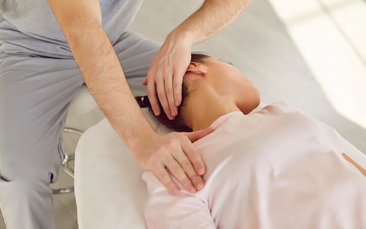 A close up of a hand stretching a patient’s neck during treatment
