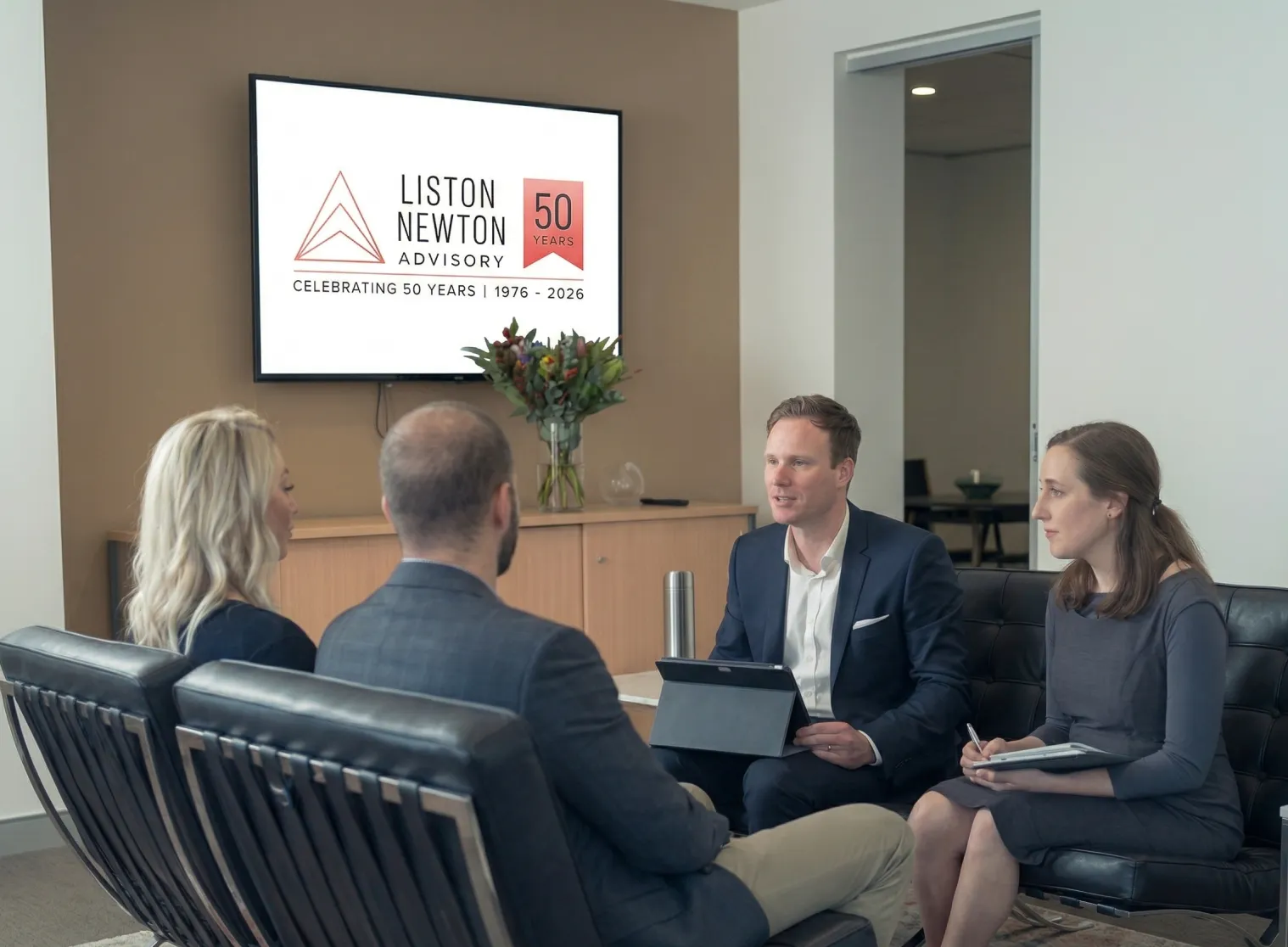 Two clients and an adviser review information on an ipad during a professional meeting in a bright, modern office.