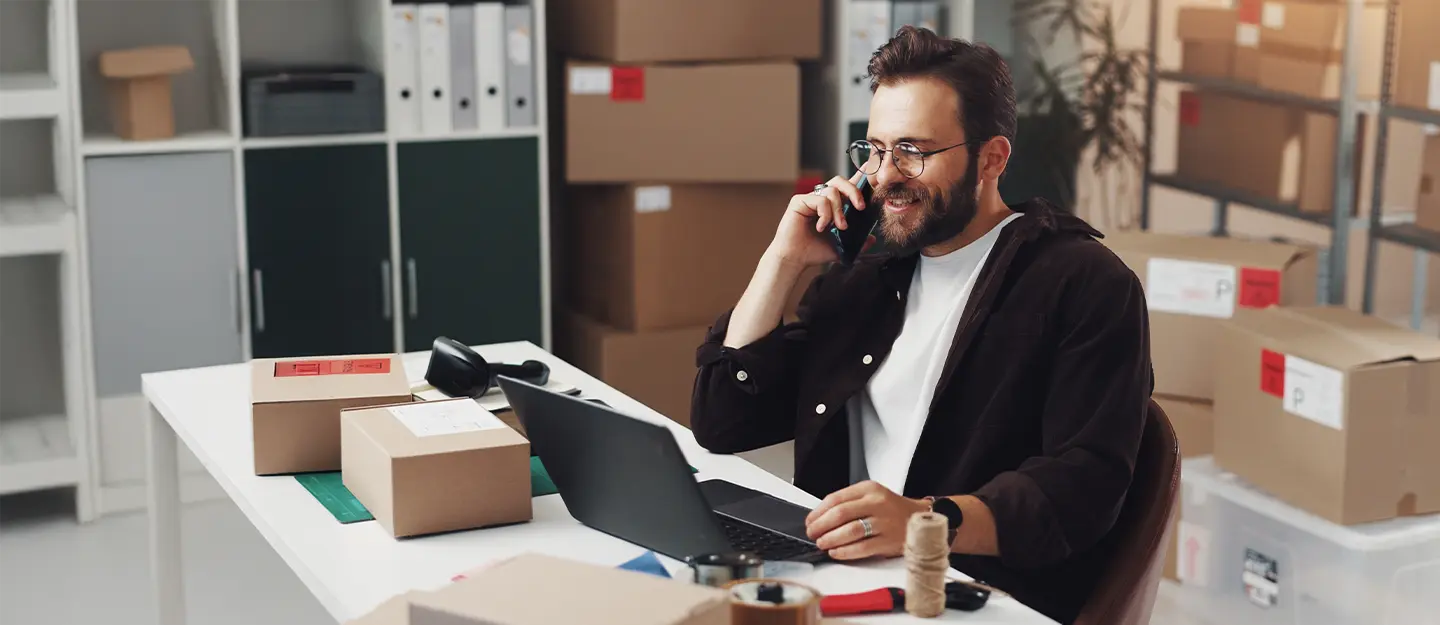 Wholesale business owner managing orders, invoices, and customer accounts from a warehouse office.