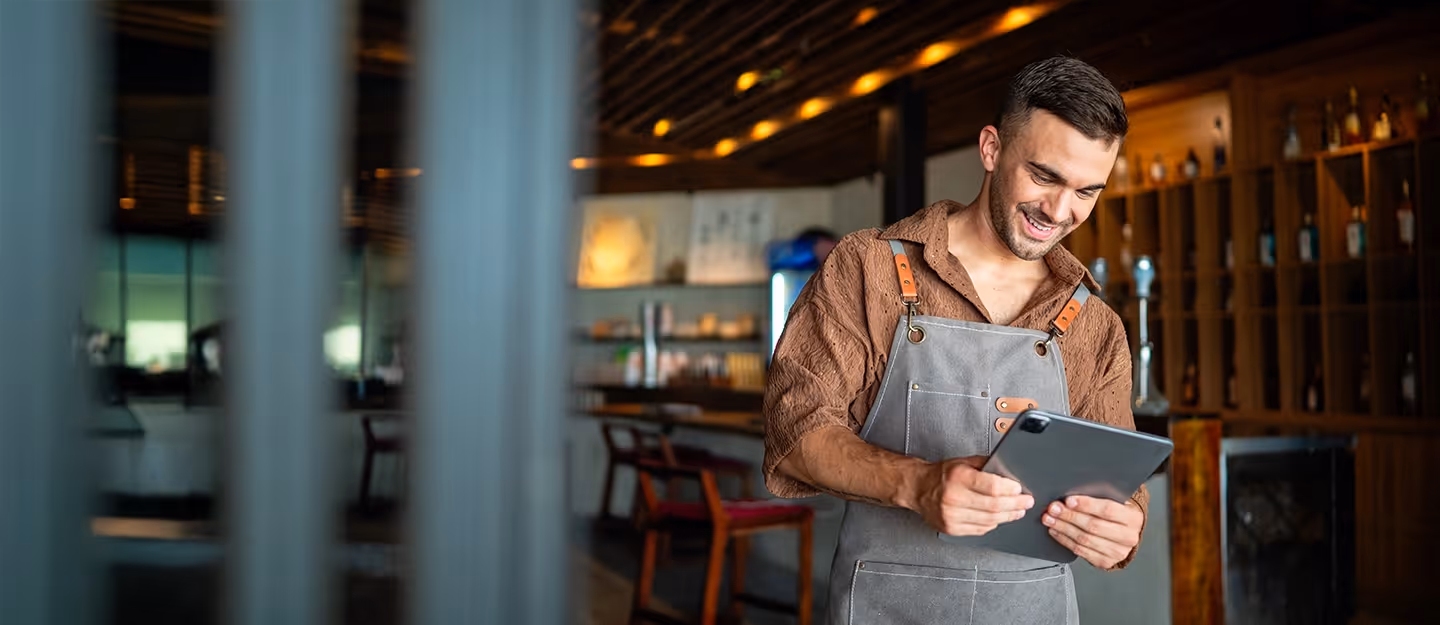 Franchise owner using a tablet inside a modern hospitality venue while managing daily business operations.