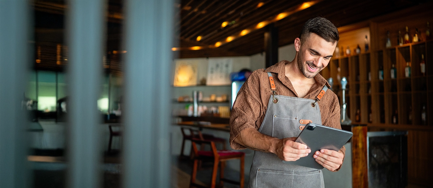Franchise owner using a tablet inside a modern hospitality venue while managing daily business operations.