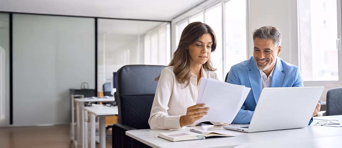 Accountant meeting with a client to review financial documents and business reports in an office setting.