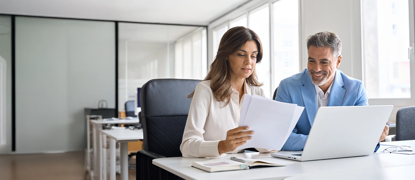 Accountant meeting with a client to review financial documents and business reports in an office setting.