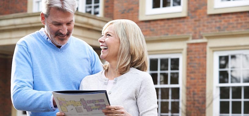 Older couple reviewing aged care planning options together outside their home to prepare for future care and financial needs.