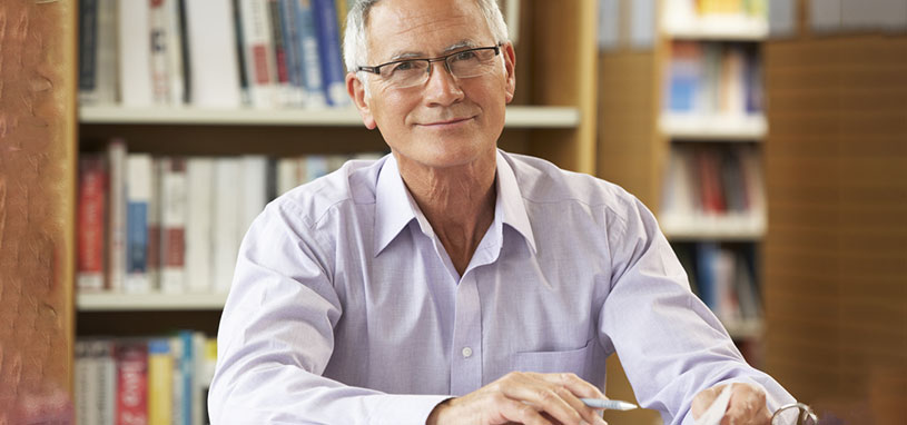 Older man reviewing aged care and financial planning documents to prepare for future care costs and arrangements.