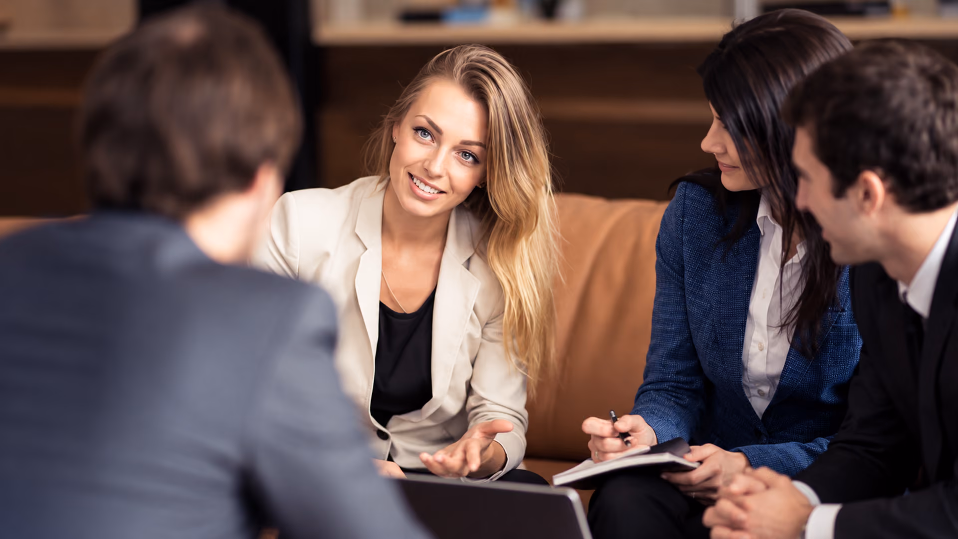 Businesswoman talking with colleagues during a professional group meeting in a modern office environment.