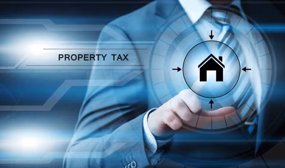 Businessman touching a digital interface with a house icon and Property Tax text on a glowing blue screen.
