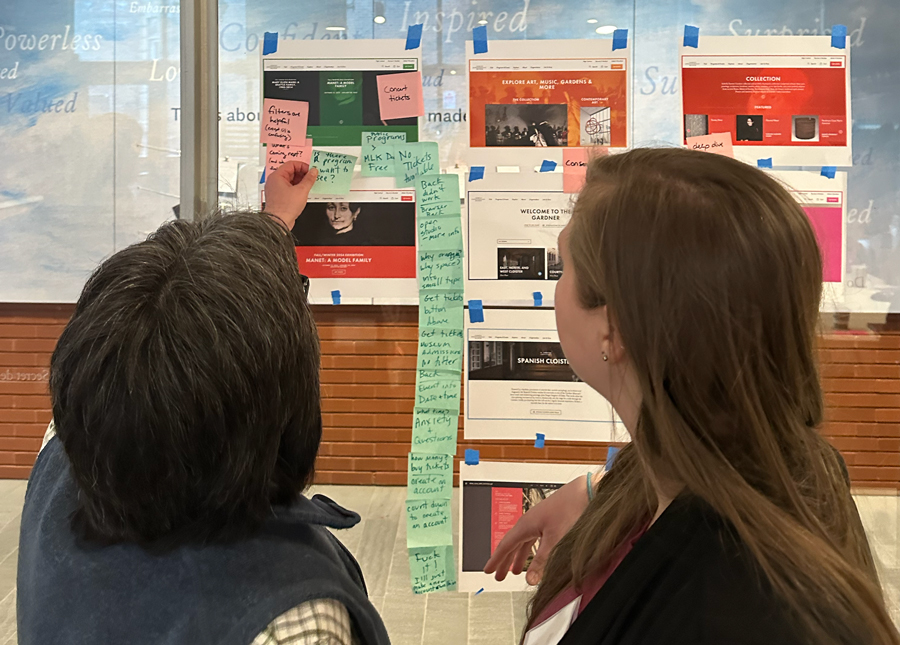 Rachel and a co-worker moving sticky notes on a printed out page from the old Museum website.