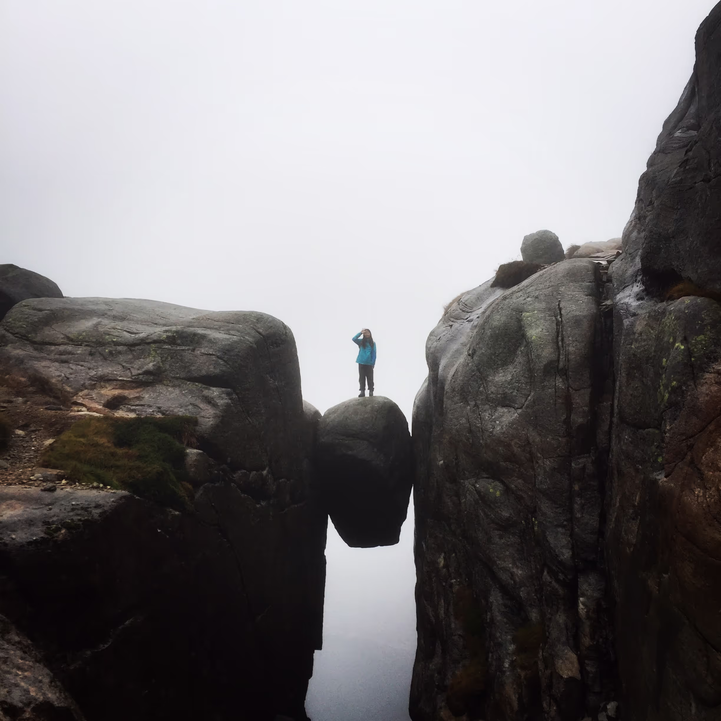 Person standing on the rock formation  Kjerag Bolt, about 700 meters above the fjord Lysefjorden