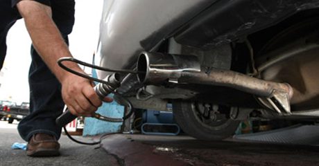 Technician inserting an emissions probe into a car tailpipe during a California smog check