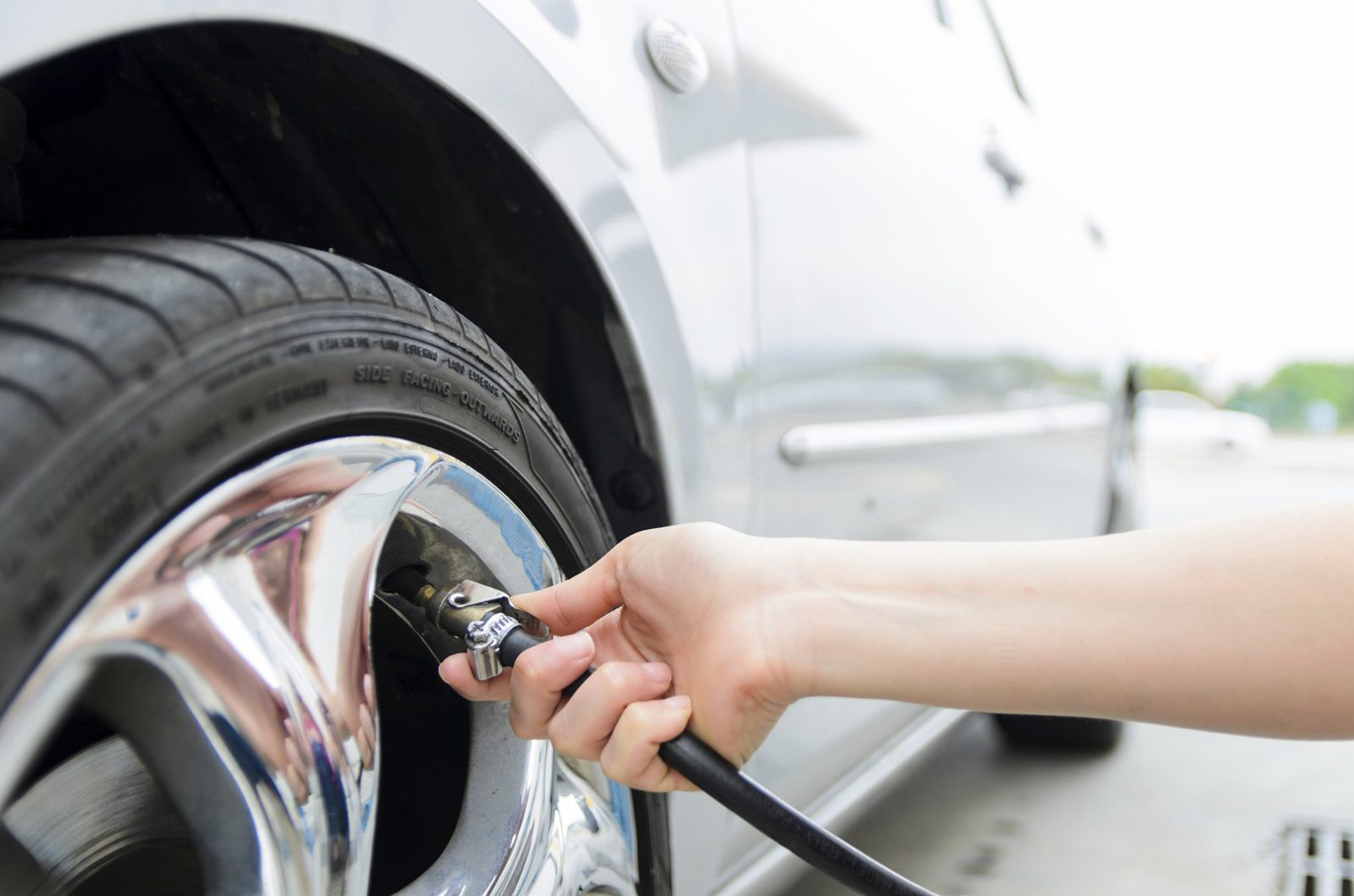 Close-up of a tire being inflated through the valve stem with an air chuck