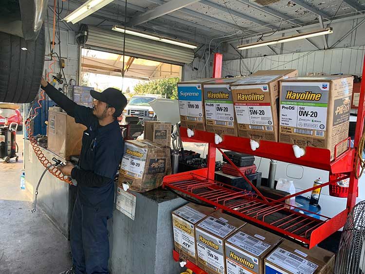 Technician at Quality Tune-Up Northgate in Sacramento checking tire pressure with an air hose