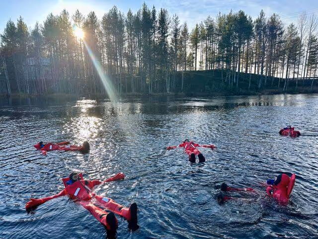 Peaceful scene of individuals in warm, dry suits floating effortlessly on a serene lake during an autumn tour.