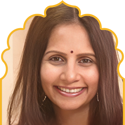 Smiling woman with long dark hair and a red bindi on her forehead.