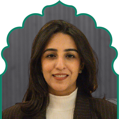 Portrait of a woman with dark hair wearing a white turtleneck and dark pinstripe blazer against a patterned background.