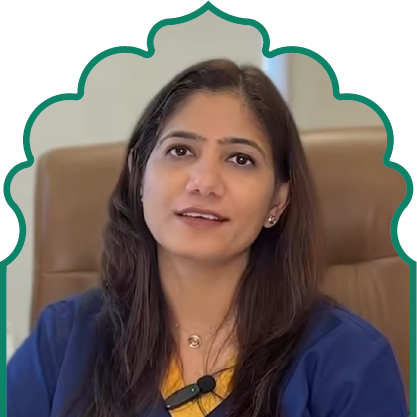 Portrait of a woman with long dark hair wearing a blue top and a yellow inner shirt, seated on a brown chair.