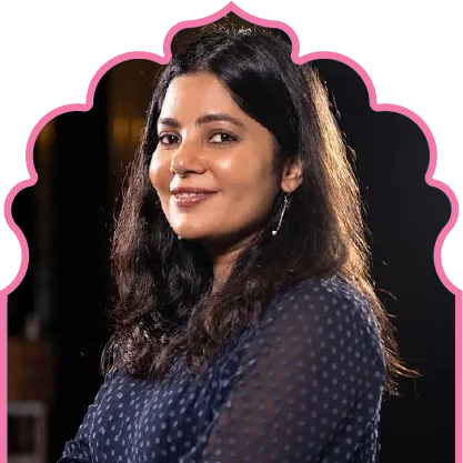 Portrait of a woman with long dark hair wearing a dark blue polka-dot blouse, smiling and looking at the camera.
