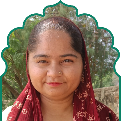 Portrait of a woman wearing a maroon patterned headscarf, standing outdoors with trees in the background.
