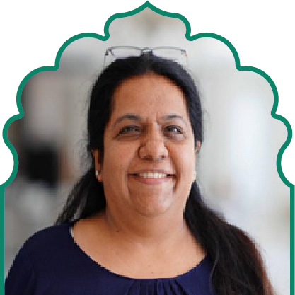Smiling woman with long dark hair wearing a navy top and glasses resting on her head.