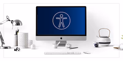 Photograph of a desktop with a computer monitor displaying an accessibility symbol.