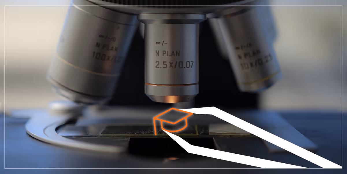 Photo of a microscope with an illustrated graduation cap being placed on the tray using tweezers.