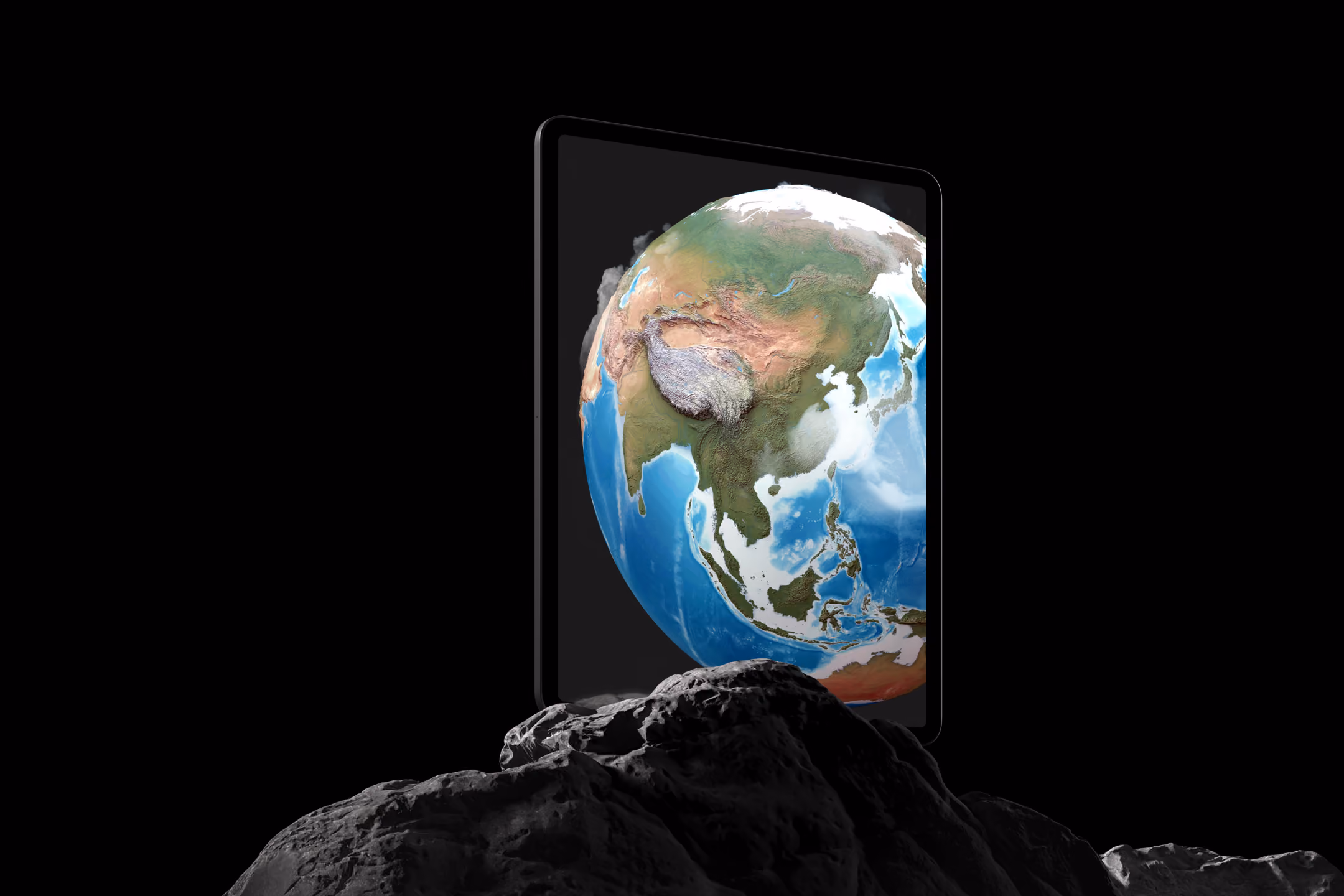 Tablet screen displaying Earth focusing on Asia, floating above dark rocky surface.